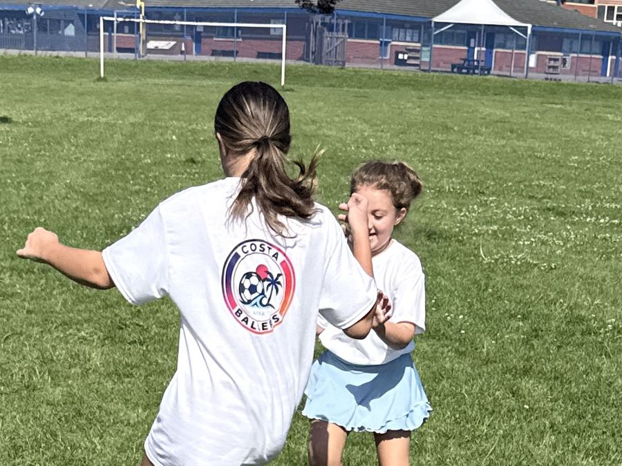 Junior Ballers players play-fighting for the ball and laughing on the pitch