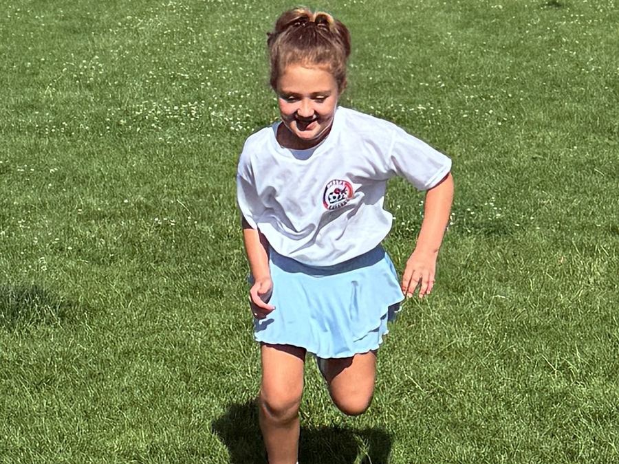 Young Mini Ballers player smiling and running with the ball